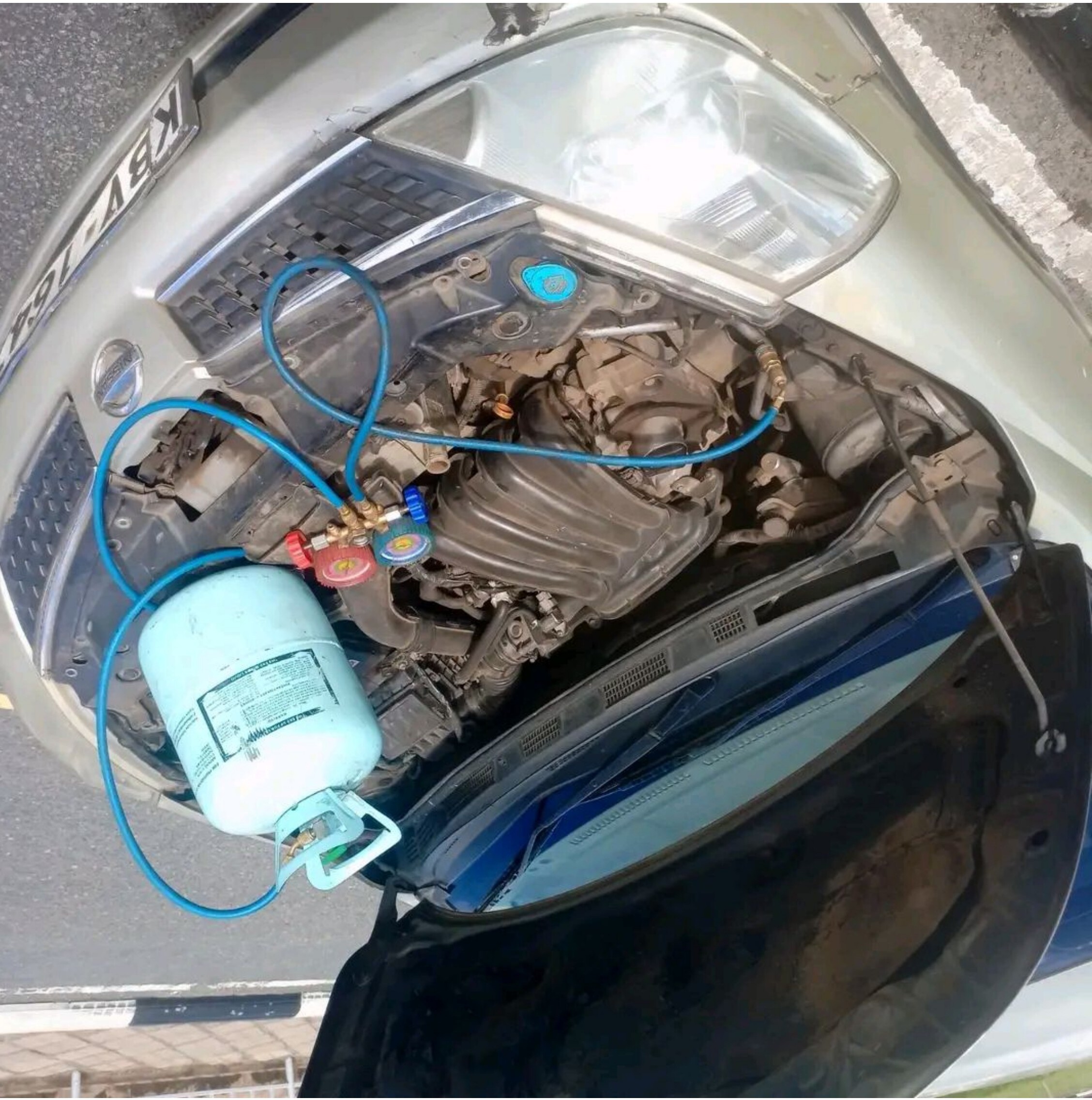 HillTech technician using a manifold gauge during car AC diagnostics